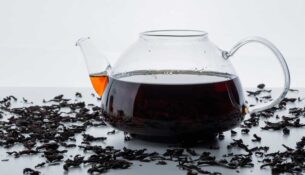 brewed-tea-glass-teapot-with-dry-black-tea-side-view-white-surface-1749887679